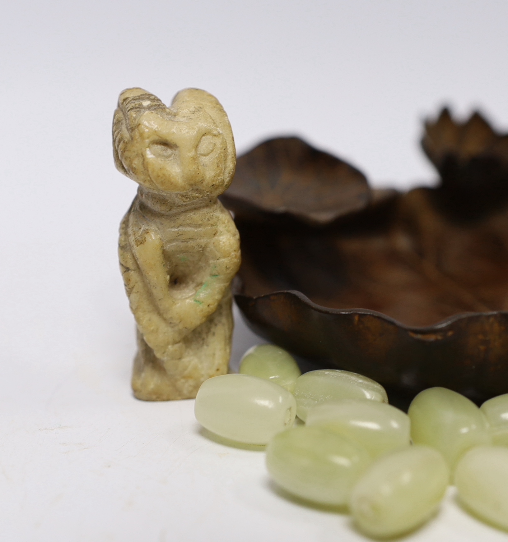 A collection of Chinese items including a bronze tray in the form of a water lily, two bowenite or jadeite discs, a soapstone cat and a bag of hardstone beads, bronze 14cm diameter